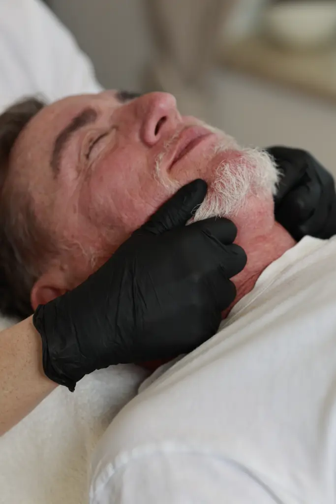 Therapeutin behandelt behutsam die Kaumuskulatur und das Kiefergelenk einer entspannt liegenden Patientin