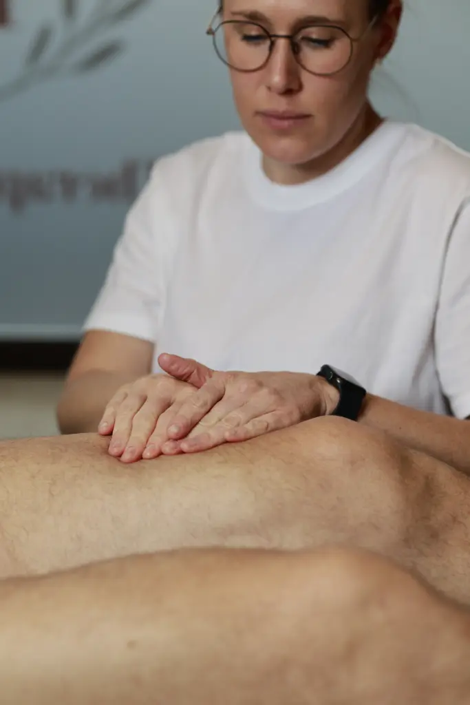 Therapeutin führt sanfte Massagegriffe am Bein einer liegenden Patientin durch, um den Lymphfluss zu fördern