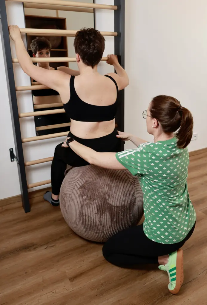 Physiotherapeutin korrigiert die Körperhaltung einer Patientin mit Skoliose bei der Schroth-Einzeltherapie